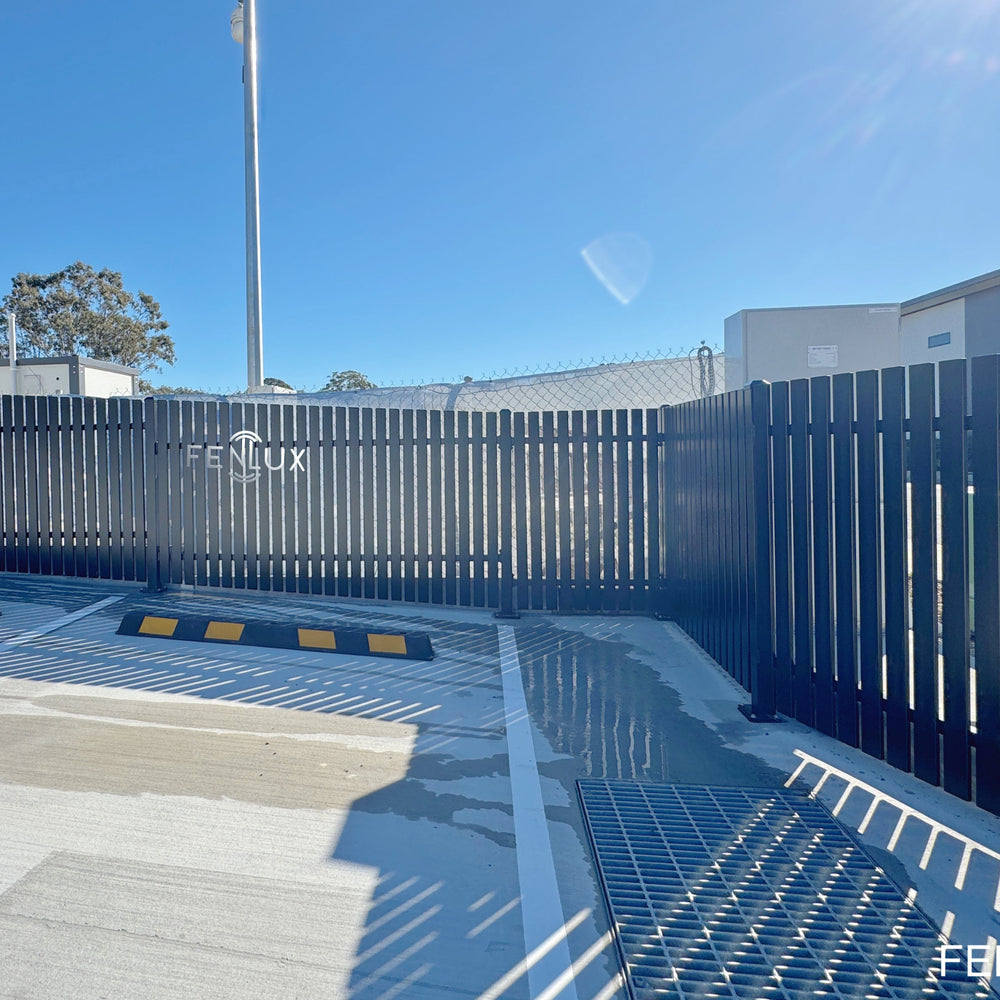 A dark gray vertical slat fence was installed around a concrete platform.