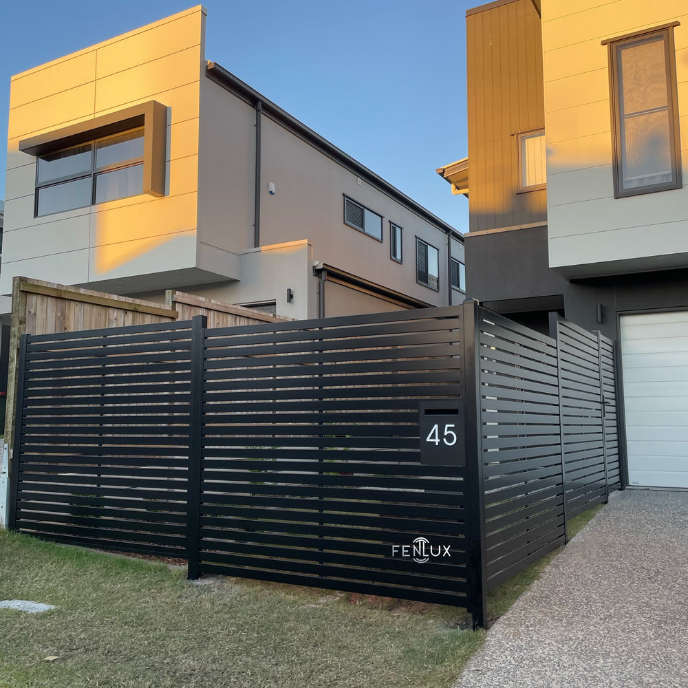 Modern house with a black horizontal slats fence and gate and 'Fenlux' branding.